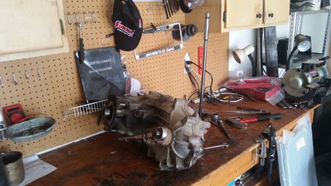 1985 Ford Bronco - Workbench setup with a transmission and various tools, including a grinder.
