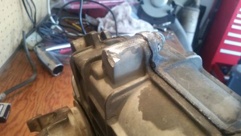 1985 Ford Bronco - A close-up view of a metal automotive component, possibly a transmission or differential housing, on a cluttered workbench.