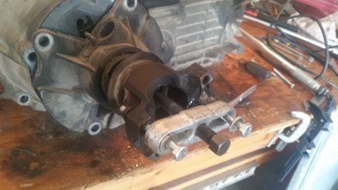 1985 Ford Bronco - Close-up of a driveshaft yoke and U-joint assembly, likely undergoing repair or maintenance on a wooden workbench.