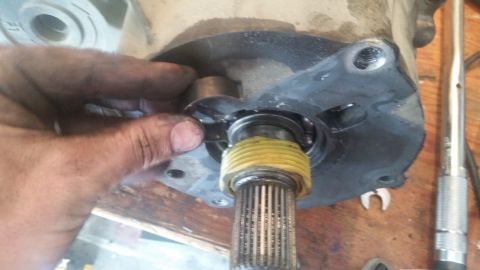 1985 Ford Bronco - Mechanic's hands work on a splined shaft and bearing assembly, likely part of a vehicle's drivetrain.