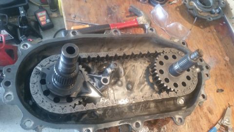 1985 Ford Bronco - Transfer case components, including chain and gears, are laid out on a workbench.