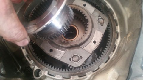 1985 Ford Bronco - A hand holds a gear over a transmission's planetary gear set, showing internal components.