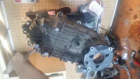 1985 Ford Bronco - A transfer case assembly is shown, with a hand pointing to a bolt on its side.