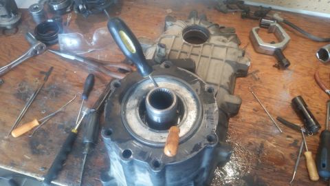 1985 Ford Bronco - A disassembled transfer case part sits on a workbench surrounded by various tools.