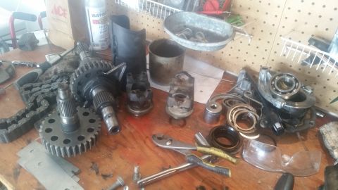 1985 Ford Bronco - Various automotive parts, possibly for a transmission or drivetrain, are spread across a workbench.