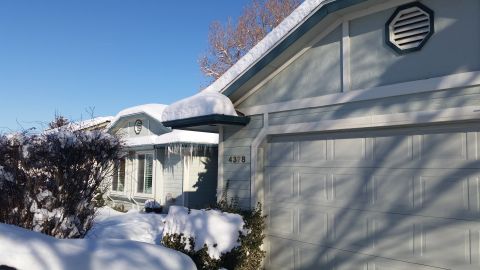 1981 Ford Bronco - A house is covered in snow with icicles hanging from the roof on a sunny day.