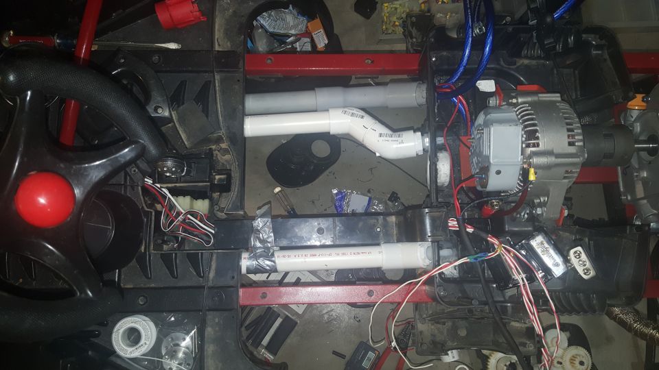 Custom wiring and PVC pipes connected to an alternator and other components