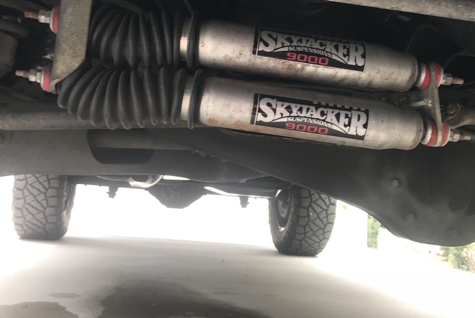 Underside view of a vehicle's rear axle with dual Skyjacker 9000 suspension shocks and off-road tires