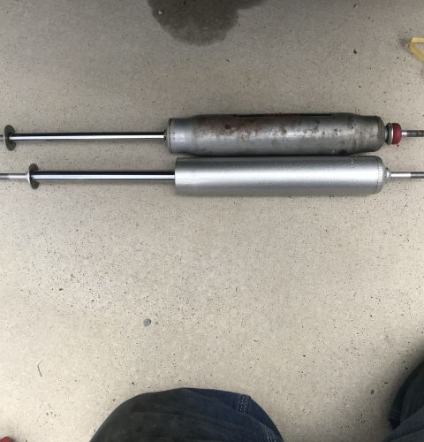 1995 Ford Bronco - Two shock absorbers are shown, one old and rusty, the other new and silver.