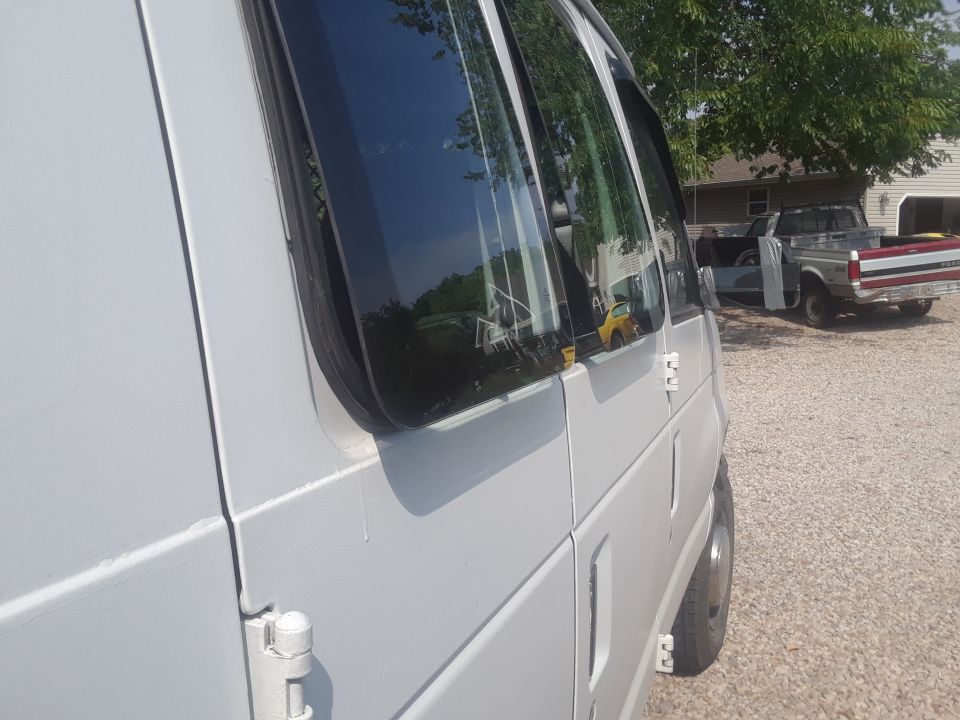 Side view of a white van with a pickup truck in the background