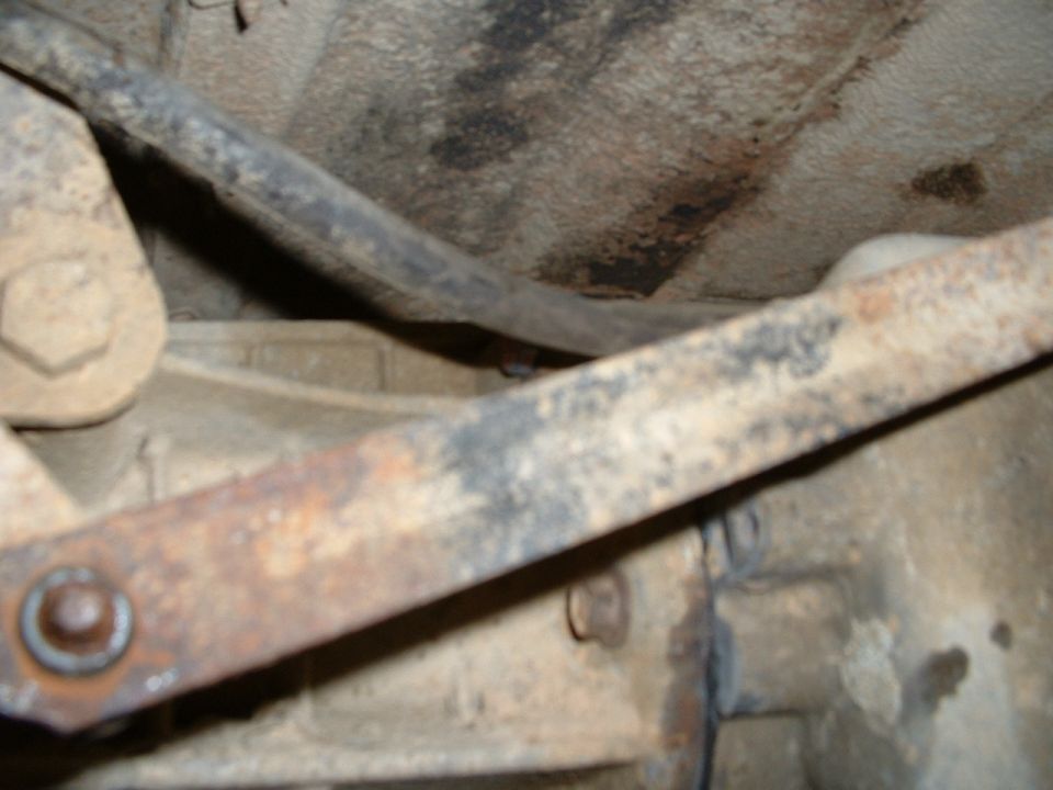 close-up of rusty metal parts and frame under a vehicle, likely the transfer case area