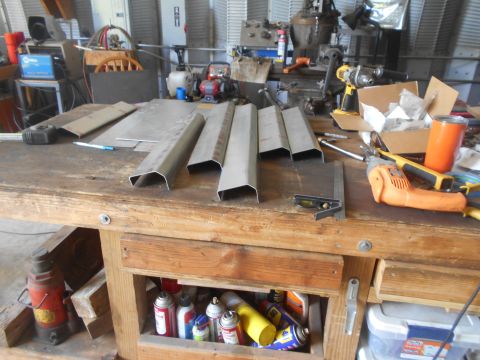 1992 Ford Bronco - Metal fabrication parts are laid out on a workbench with various tools and cans of spray paint.