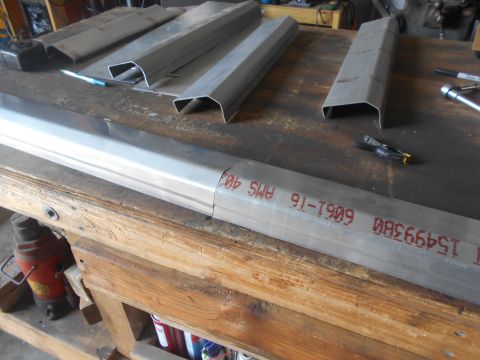 1992 Ford Bronco - Metal fabrication parts are arranged on a wooden workbench with tools and a jack visible.