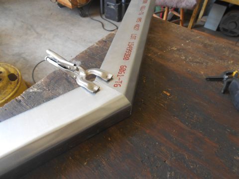 1992 Ford Bronco - Metal tubing is held in place with a clamp on a workbench, with visible text on the tubing.
