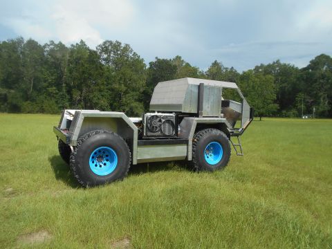 1992 Ford Bronco - This custom vehicle has large tires and an exposed engine cooling system, parked in a grassy field.