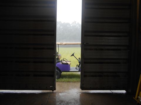 1992 Ford Bronco - A purple golf cart sits on wet grass as seen through an open garage door.