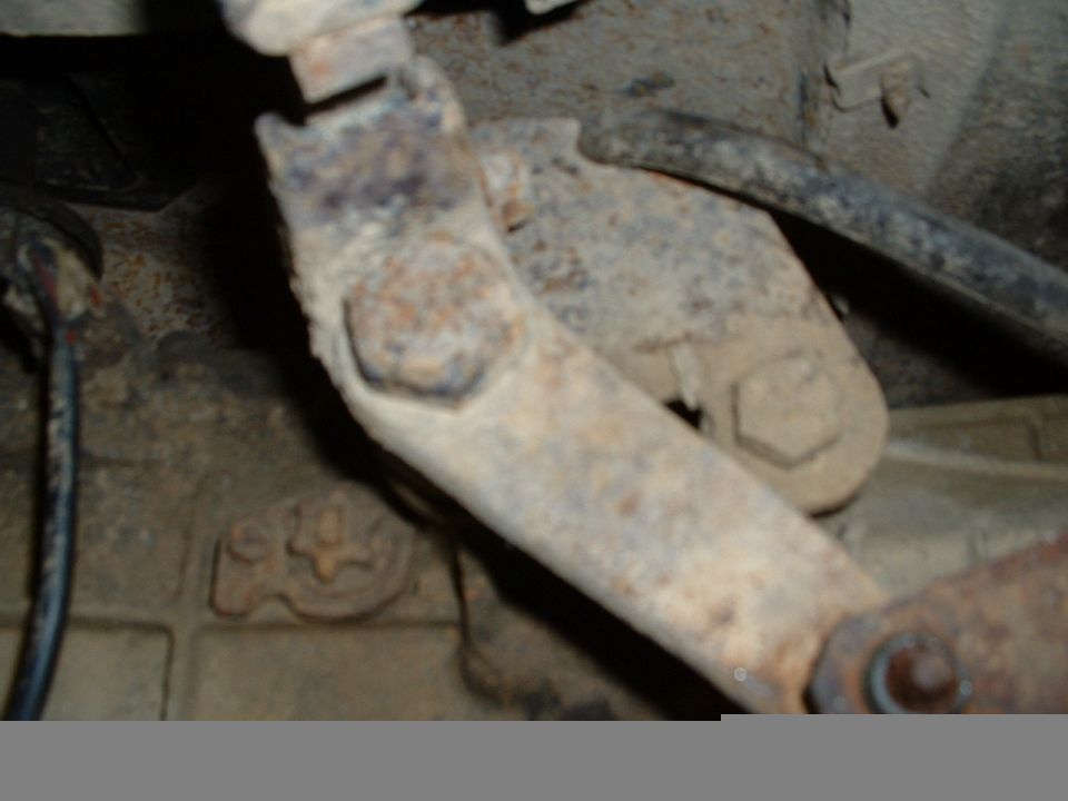 Rusted metal bracket and bolts on a vehicle component