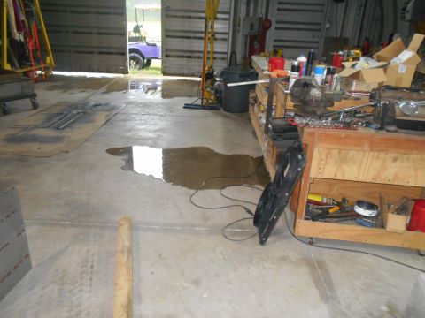 1992 Ford Bronco - A purple golf cart is visible through the open doors of a garage, with tools and supplies on a workbench inside.