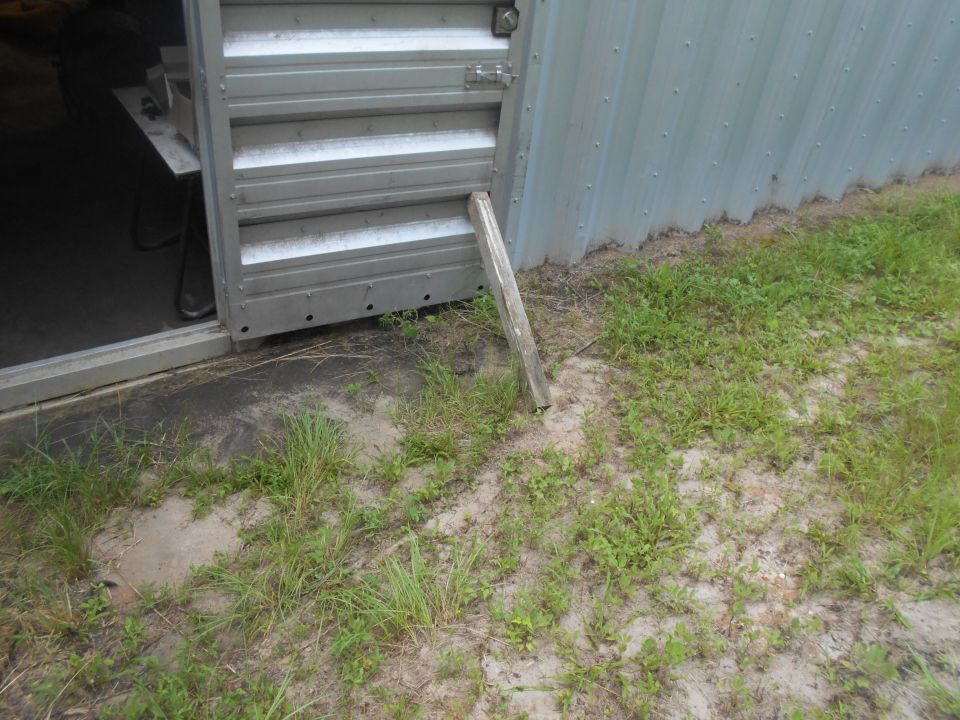 Metal building with an open door and a wooden prop holding it open