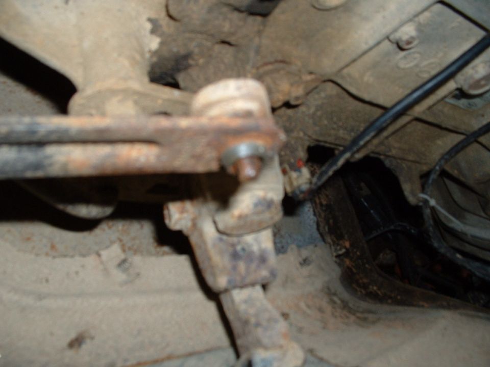 close-up of a rusted suspension component with a black wire running nearby