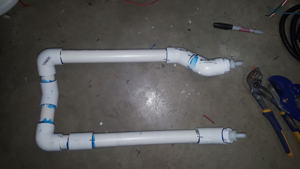 Assembled PVC pipes with fittings and blue tape markings, next to pliers and a marker