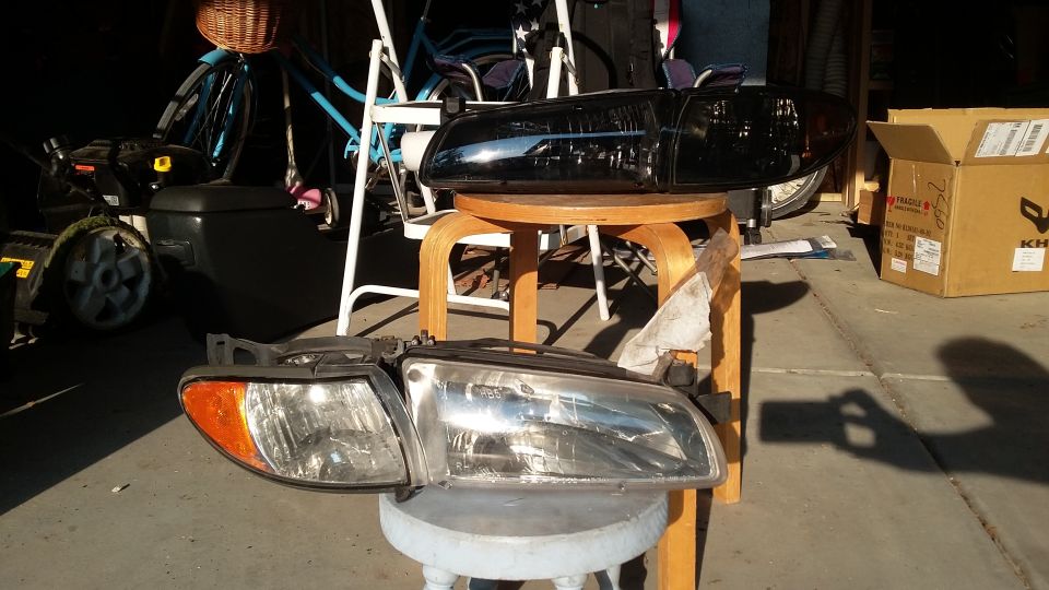 Aftermarket headlight assemblies and a black spoiler in a garage