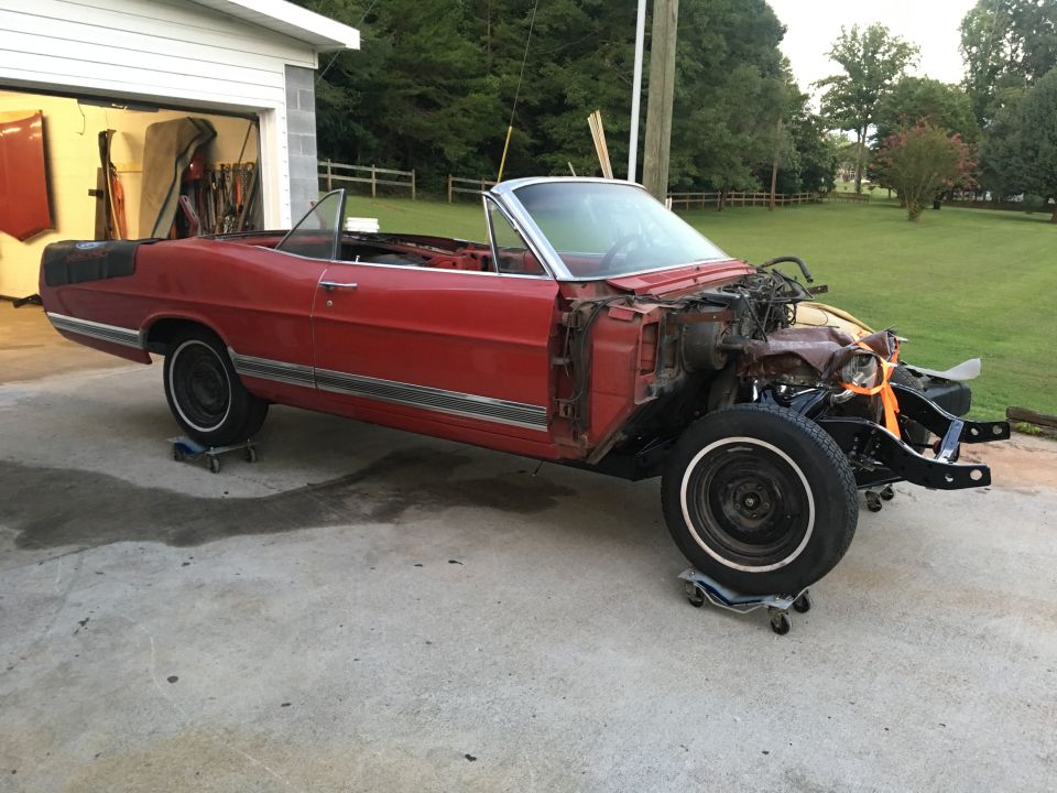 Red convertible classic car on dollies with front end disassembled.