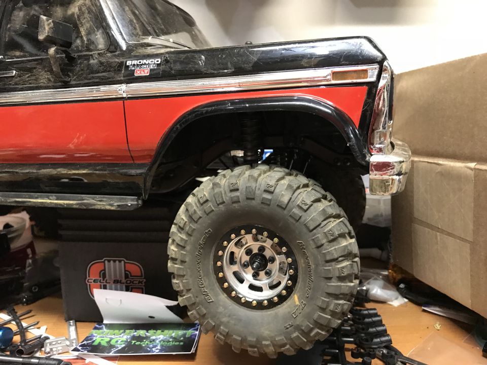 RC rock crawler truck with large off-road tires and red/black paint.