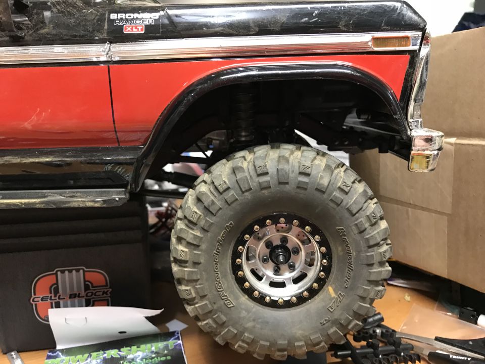 RC car body with red and black paint, large off-road tire and wheel.