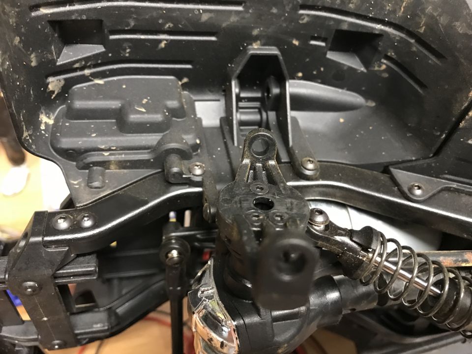 Close-up of RC car suspension and steering parts, dusty.