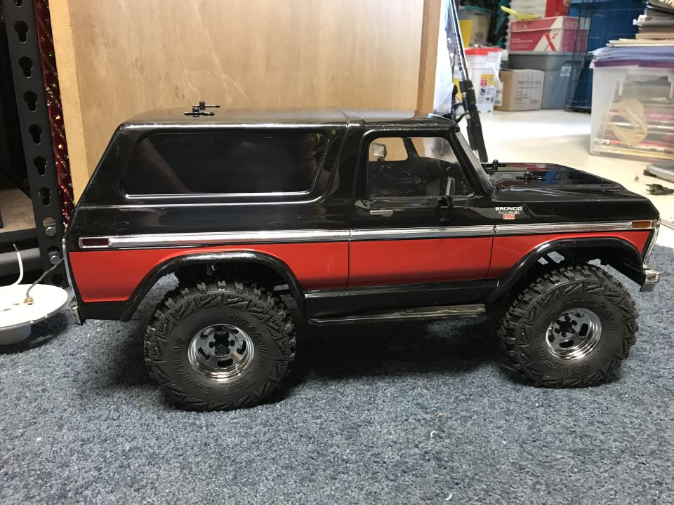 Side view of a black and red Ford Bronco model truck with off-road tires.