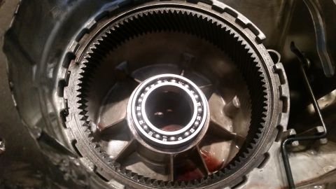 1985 Ford Bronco - A close-up view of the internal components of a vehicle's transmission, showing a ring gear and a bearing with ball bearings. Red fluid is…