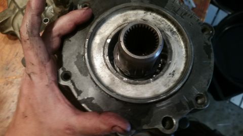 1985 Ford Bronco - A hand with grease on it is holding a metal automotive part with splines visible in the center. The part appears to be a component of a dri…