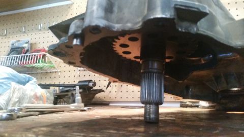 1985 Ford Bronco - A close-up, low-angle shot shows the splined shaft of a transmission or transfer case protruding from the bottom of a metal housing. A larg…