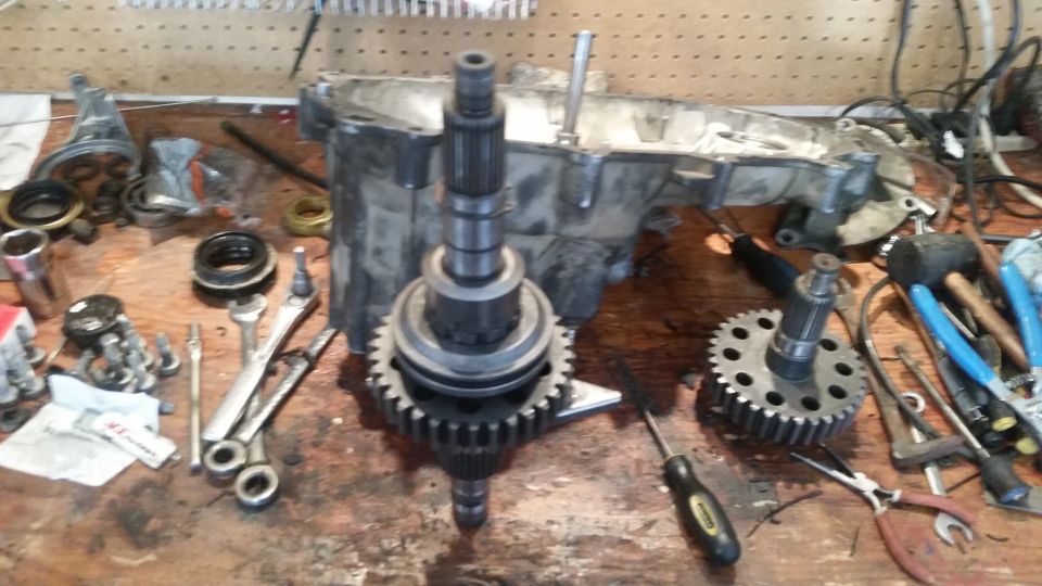 Workbench with transmission parts and tools, including gears and a metal casing.