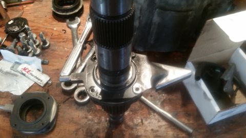 1985 Ford Bronco - A close-up view of a vehicle's drivetrain component, possibly a driveshaft or axle, is shown on a wooden workbench amidst various tools and…