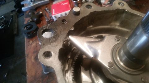 1985 Ford Bronco - A close-up view of a damaged metal housing, possibly part of a vehicle's drivetrain, with a gear visible inside. The housing appears to be…