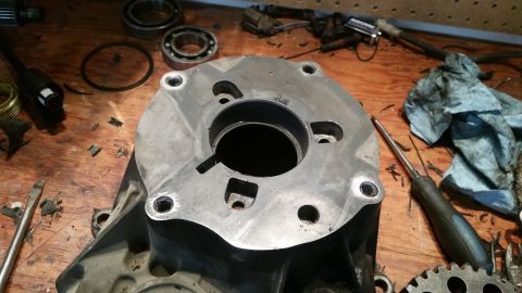 1985 Ford Bronco - A close-up view of a disassembled metal component, likely part of a vehicle's drivetrain, resting on a wooden workbench. Various tools and…