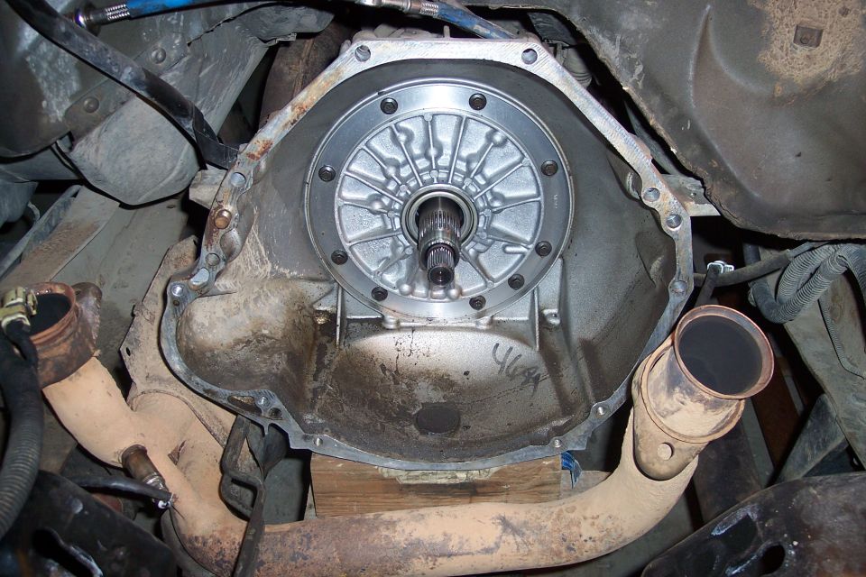 Transmission bell housing with torque converter and exhaust pipes.