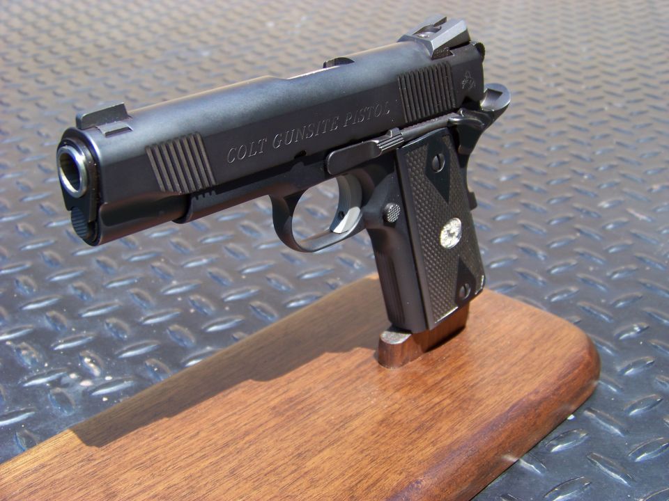 Black Colt Gunsite Pistol on a wooden stand.