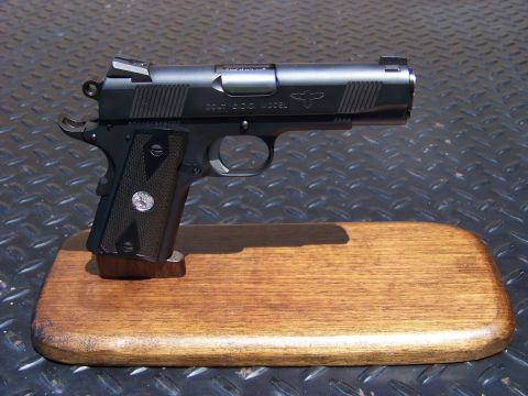 1995 Mercury Grand Marquis - A black Colt 1911 pistol is displayed on a wooden stand against a diamond plate background.