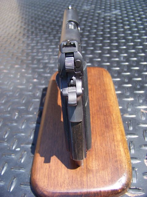 1995 Mercury Grand Marquis - A close-up, top-down view of the rear sight and slide of a black semi-automatic pistol. The pistol is resting on a wooden display base.