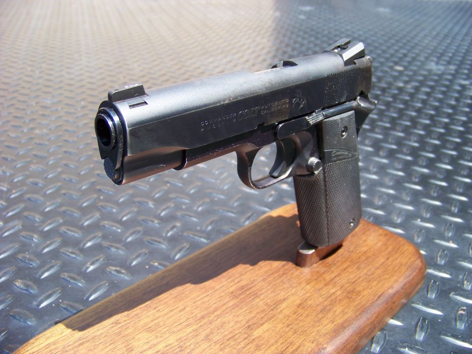 Black semi-automatic pistol on a wooden stand.