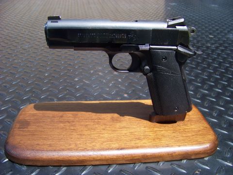 1995 Mercury Grand Marquis - A black semi-automatic handgun is displayed on a wooden stand, which is placed on a diamond plate surface.