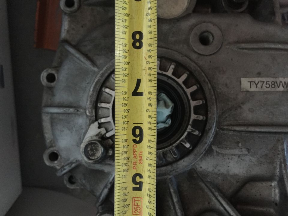 Close-up of a silver vehicle part with a yellow measuring tape showing inches and fractions.