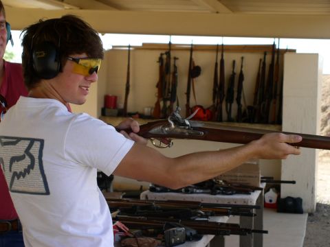 1990 Ford Bronco - Man at a shooting range with an antique rifle and other firearms on display.
