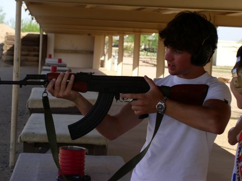 1990 Ford Bronco - A person at an outdoor shooting range holds an AK-47 rifle while wearing ear protection.