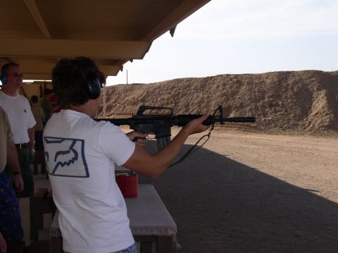 1990 Ford Bronco - Man at shooting range with rifle, wearing headphones and a white t-shirt with a Fox logo.