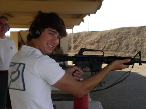 1990 Ford Bronco - A person aims a rifle at an outdoor shooting range, wearing headphones.
