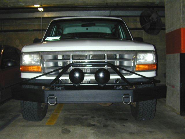 White Ford Bronco with aftermarket bumper and lights, parked indoors